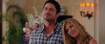 Movie still from “The Bounty Hunter” (2010), directed by Andy Tennant – A man and a woman standing next to each other in front of flowers; Close Up shot, Over the shoulder angle