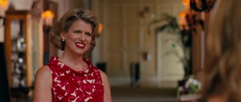 Movie still from “The Bounty Hunter” (2010), directed by Andy Tennant – A woman in a red and white dress smiling for the camera; Medium shot, Over the shoulder angle