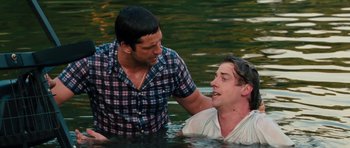 Movie still from “The Bounty Hunter” (2010), directed by Andy Tennant – Two men are in the water and one of them has his arm around the other man; Medium shot, Over the shoulder angle