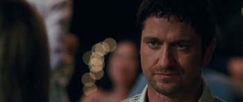 Movie still from “The Bounty Hunter” (2010), directed by Andy Tennant – A man's face in front of blurry lights; Close Up shot, Over the shoulder angle