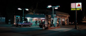 Movie still from “The Bounty Hunter” (2010), directed by Andy Tennant – A gas station at night with cars parked on the side of the road; Extreme Wide shot, High angle