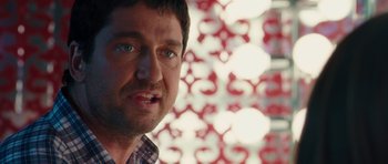 Movie still from “The Bounty Hunter” (2010), directed by Andy Tennant – A man's face in front of a red and white background; Close Up shot, Over the shoulder angle