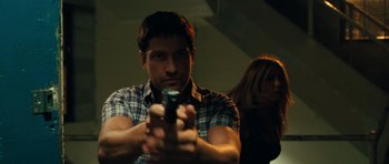 Movie still from “The Bounty Hunter” (2010), directed by Andy Tennant – A man holding a gun while standing next to a woman; Close Up shot, Low angle