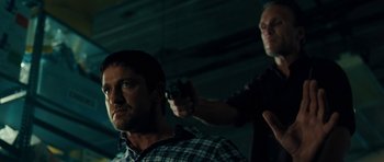 Movie still from “The Bounty Hunter” (2010), directed by Andy Tennant – A man holding a handgun while standing next to another man; Close Up shot, Over the shoulder angle