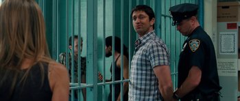 Movie still from “The Bounty Hunter” (2010), directed by Andy Tennant – A man standing next to a metal fence; Medium shot, Over the shoulder angle