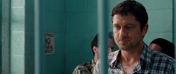 Movie still from “The Bounty Hunter” (2010), directed by Andy Tennant – A man standing next to another man in front of a blue wall; Close Up shot, Over the shoulder angle