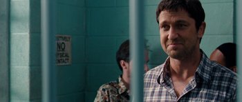 Movie still from “The Bounty Hunter” (2010), directed by Andy Tennant – A man standing next to another man behind a fence; Close Up shot, Over the shoulder angle