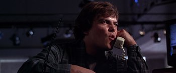 Movie still from “The Cable Guy” (1996), directed by Ben Stiller – A man talking on a phone while sitting in a chair; Close Up shot, Low angle