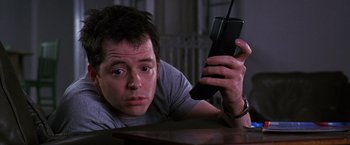 Movie still from “The Cable Guy” (1996), directed by Ben Stiller – A man looking at a cell phone while sitting at a table; Close Up shot, Low angle