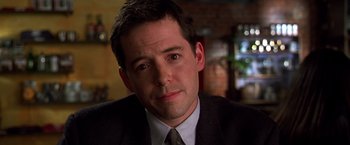 Movie still from “The Cable Guy” (1996), directed by Ben Stiller – A person wearing a suit and tie; Close Up shot, Over the shoulder angle