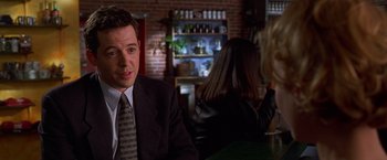 Movie still from “The Cable Guy” (1996), directed by Ben Stiller – A man in a suit sitting at a table; Close Up shot, Over the shoulder angle