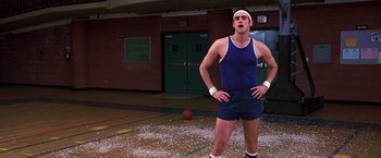 Movie still from “The Cable Guy” (1996), directed by Ben Stiller – A man standing on a basketball court with his hands on his hips; Medium shot, Low angle