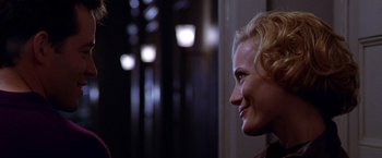 Movie still from “The Cable Guy” (1996), directed by Ben Stiller – A woman with blonde hair is smiling at the camera; Close Up shot, Over the shoulder angle