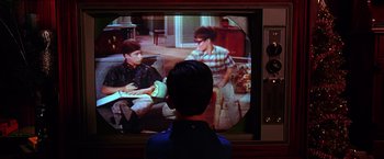 Movie still from “The Cable Guy” (1996), directed by Ben Stiller – A young boy is watching television with two friends; Wide shot, Over the shoulder angle