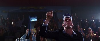 Movie still from “The Cable Guy” (1996), directed by Ben Stiller – A man wearing a paper crown is raising his fist; Medium shot, Low angle