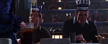 Movie still from “The Cable Guy” (1996), directed by Ben Stiller – Two men sitting at a table in front of a crowd; Medium shot, Low angle