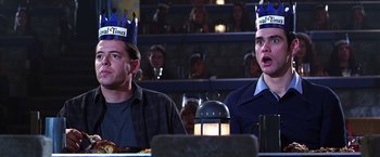 Movie still from “The Cable Guy” (1996), directed by Ben Stiller – Two men sitting in front of a crowd wearing paper crowns; Medium shot, Low angle