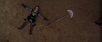 Movie still from “The Cable Guy” (1996), directed by Ben Stiller – An overhead view of a person laying on the ground holding a weapon; Wide shot, Overhead angle