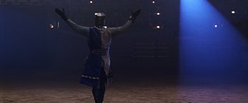 Movie still from “The Cable Guy” (1996), directed by Ben Stiller – A person in a knight's outfit is standing in a dark arena; Wide shot, High angle