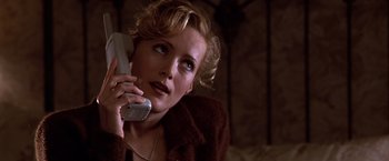 Movie still from “The Cable Guy” (1996), directed by Ben Stiller – A woman talking on a cell phone while wearing a brown jacket; Close Up shot, High angle