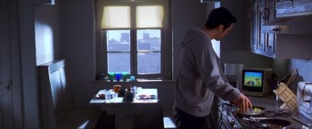 Movie still from “The Cable Guy” (1996), directed by Ben Stiller – A man standing in front of a table in front of a window; Medium shot, Low angle