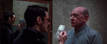 Movie still from “The Cable Guy” (1996), directed by Ben Stiller – A man looking at another man holding up a dollar bill; Close Up shot, Over the shoulder angle