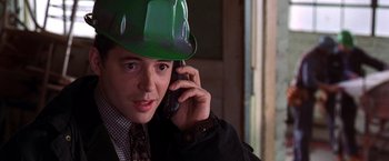 Movie still from “The Cable Guy” (1996), directed by Ben Stiller – A man wearing a hard hat talking on a cell phone; Close Up shot, High angle