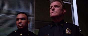 Movie still from “The Cable Guy” (1996), directed by Ben Stiller – A man in a police uniform looking up; Close Up shot, Low angle