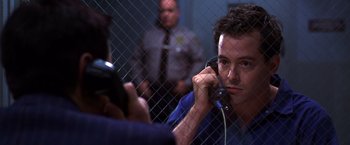 Movie still from “The Cable Guy” (1996), directed by Ben Stiller – A man talking on a phone in front of a fence; Close Up shot, Low angle