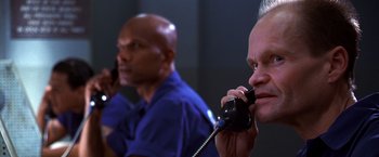 Movie still from “The Cable Guy” (1996), directed by Ben Stiller – A man on the phone with another man in the background; Close Up shot, Low angle