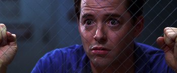 Movie still from “The Cable Guy” (1996), directed by Ben Stiller – A person behind a chain link fence; Close Up shot, Low angle