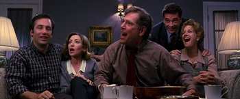 Movie still from “The Cable Guy” (1996), directed by Ben Stiller – A group of people that are sitting around a table; Medium shot, Over the shoulder angle