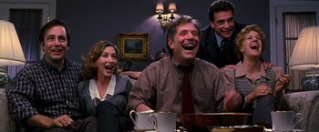 Movie still from “The Cable Guy” (1996), directed by Ben Stiller – A group of people sitting in a room laughing together; Medium shot, High angle