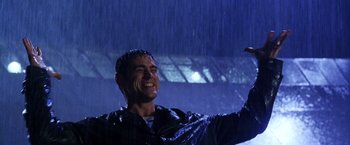 Movie still from “The Cable Guy” (1996), directed by Ben Stiller – A man in a black leather jacket standing in the rain; Medium shot, Low angle