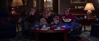 Movie still from “The Cable Guy” (1996), directed by Ben Stiller – A group of people sitting around a table eating food; Wide shot, High angle