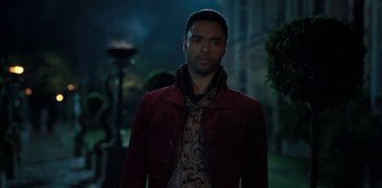 Movie still from “Bridgerton” (2020), created by Chris Van Dusen – A man wearing a red jacket standing in a park; Medium shot, Over the shoulder angle