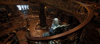 Movie still from “The Dark Crystal: Age of Resistance” (2019), created by Jim Henson – A woman reading a book in a room filled with books; Wide shot, High angle