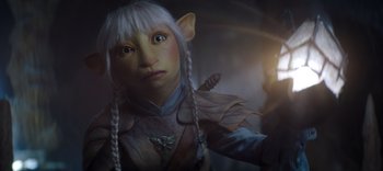 Movie still from “The Dark Crystal: Age of Resistance” (2019), created by Jim Henson – A person wearing a costume with long white hair; Close Up shot, High angle