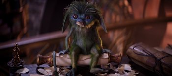 Movie still from “The Dark Crystal: Age of Resistance” (2019), created by Jim Henson – A green and blue creature sitting on top of a piece of paper; Medium shot, High angle