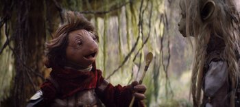 Movie still from “The Dark Crystal: Age of Resistance” (2019), created by Jim Henson – A stuffed animal holding a wooden spoon in its mouth; Close Up shot, Over the shoulder angle
