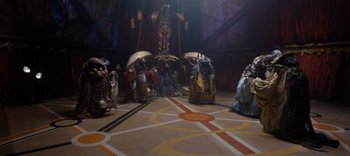 Movie still from “The Dark Crystal: Age of Resistance” (2019), created by Jim Henson – A group of people dressed up in costumes and holding umbrellas; Wide shot, High angle