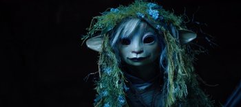 Movie still from “The Dark Crystal: Age of Resistance” (2019), created by Jim Henson – A person wearing a costume with a blue wig; Extreme Close Up shot, High angle