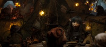 Movie still from “The Dark Crystal: Age of Resistance” (2019), created by Jim Henson – A woman sitting at a table in a dark room; Medium shot, High angle
