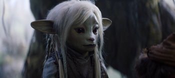 Movie still from “The Dark Crystal: Age of Resistance” (2019), created by Jim Henson – A woman with long white hair is wearing a mask; Close Up shot, High angle