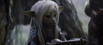 Movie still from “The Dark Crystal: Age of Resistance” (2019), created by Jim Henson – A woman with white hair holding a stick; Close Up shot, High angle
