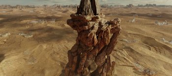 Movie still from “The Dark Crystal: Age of Resistance” (2019), created by Jim Henson – An aerial view of a rock formation in the middle of the desert; Extreme Wide shot, High angle