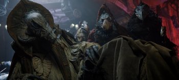 Movie still from “The Dark Crystal: Age of Resistance” (2019), created by Jim Henson – A group of people dressed in costumes in a room; Close Up shot, Low angle