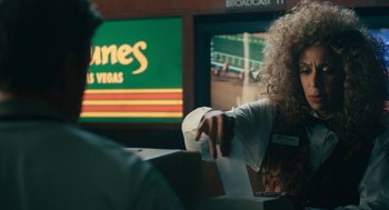 Movie still from “Air” (2023), directed by Ben Affleck – A person sitting in front of a tv holding a paper towel; Close Up shot, Over the shoulder angle