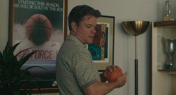 Movie still from “Air” (2023), directed by Ben Affleck – A man holding an orange in his hands; Medium shot, Over the shoulder angle