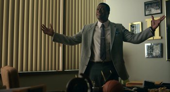 Movie still from “Air” (2023), directed by Ben Affleck – A man standing in a room with his arms outstretched; Medium shot, Low angle